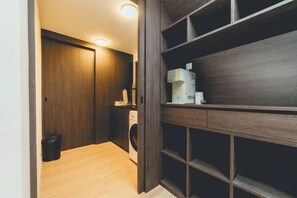 A hallway with a wooden floor, a washing machine, and a shelf unit with storage compartments. - Sunway GRID Residence Legoland (Iskandar Puteri)