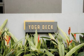 A sign labeled "YOGA DECK" on a building facade, surrounded by green foliage. - Sunway GRID Residence Legoland (Iskandar Puteri)