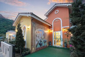 A building with a mural, a green lawn, and a mountain backdrop. - Venice de Pool Villa, Marino Khaoyai (Pak Chong)