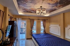 Une chambre à coucher avec un lit, une peinture murale au plafond, un lustre et une vue par la fenêtre.