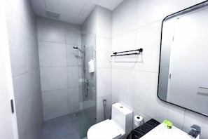 Ein modernes Badezimmer mit Duschkabine aus Glas, Toilette und Waschbecken mit Spiegel darüber.