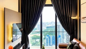 Un salon moderne doté d’une grande fenêtre, d’un téléviseur fixé au mur et d’un canapé en cuir.