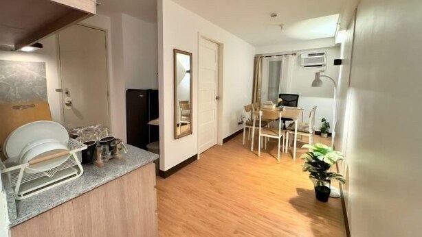 Een kleine keuken met een aanrecht, een eethoek met stoelen, een tafel en een potplant.