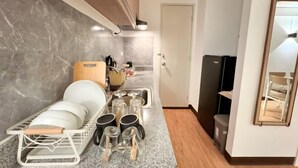 Een keuken met een afdruiprek, pannen en een magnetron.