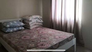 A bedroom with a bed, pillows, and a window with curtains.