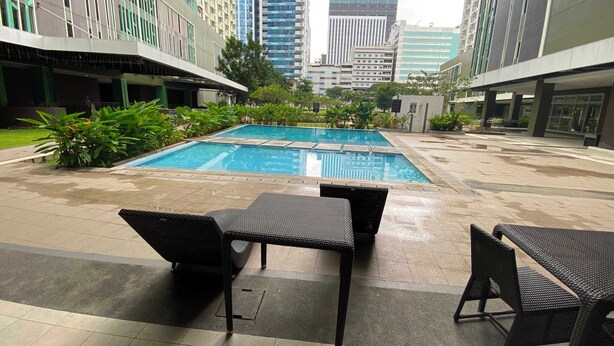 A rooftop pool area with lounge chairs and a view of surrounding high-rise buildings.