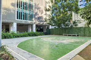 An outdoor basketball court with a green surface, surrounded by a low fence and greenery. - New Minimalist Condo at Cebu I.T. Park Avida Riala (Cebu City)