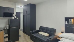 A compact hotel room with a kitchenette, a sofa bed, a wardrobe, and a bedside table with a lamp. - New Minimalist Condo at Cebu I.T. Park Avida Riala (Cebu City)