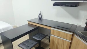 A compact kitchenette with a black countertop, two black bar stools, wooden cabinets, and a black range hood. - New Minimalist Condo at Cebu I.T. Park Avida Riala (Cebu City)