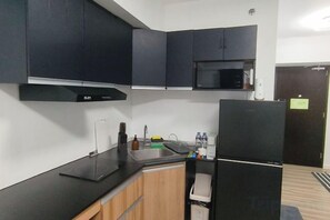 A kitchen with black cabinets, a microwave, and a refrigerator. - New Minimalist Condo at Cebu I.T. Park Avida Riala (Cebu City)
