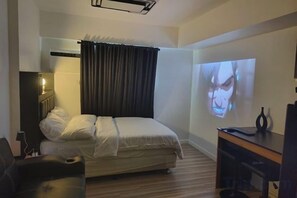 A bedroom with a bed, a desk, a chair, a television, and a projector screen. - New Minimalist Condo at Cebu I.T. Park Avida Riala (Cebu City)