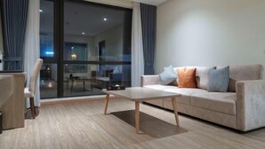A modern living room with a sofa, a coffee table, and a dining area with a chair. - Hung Vuong Hotel (Mong Cai)