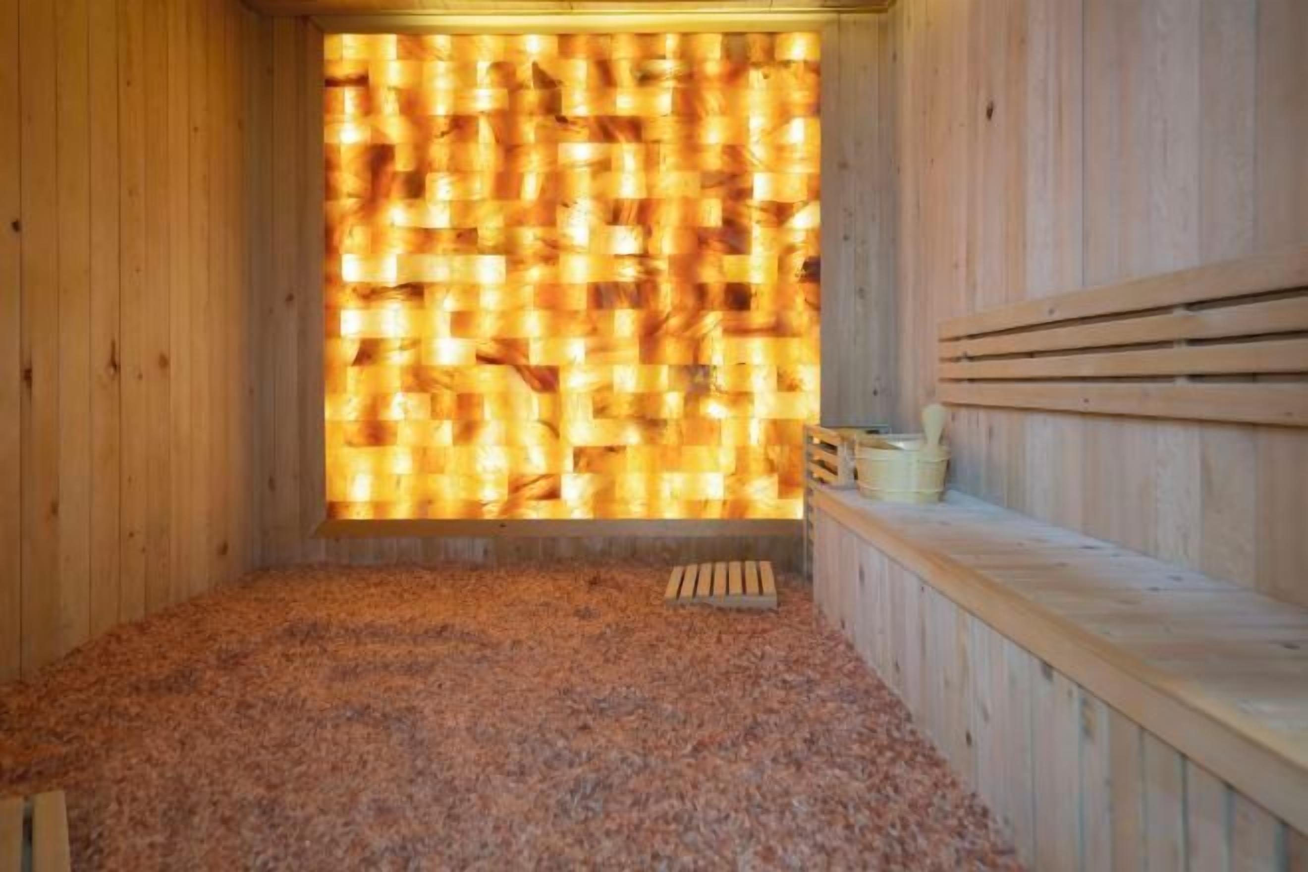 Una sauna de madera con pared de listones, un banco y una pequeña mesa de madera.