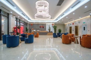 A modern lobby with seating areas, a reception desk, and a large chandelier. - Hung Vuong Hotel (Mong Cai)