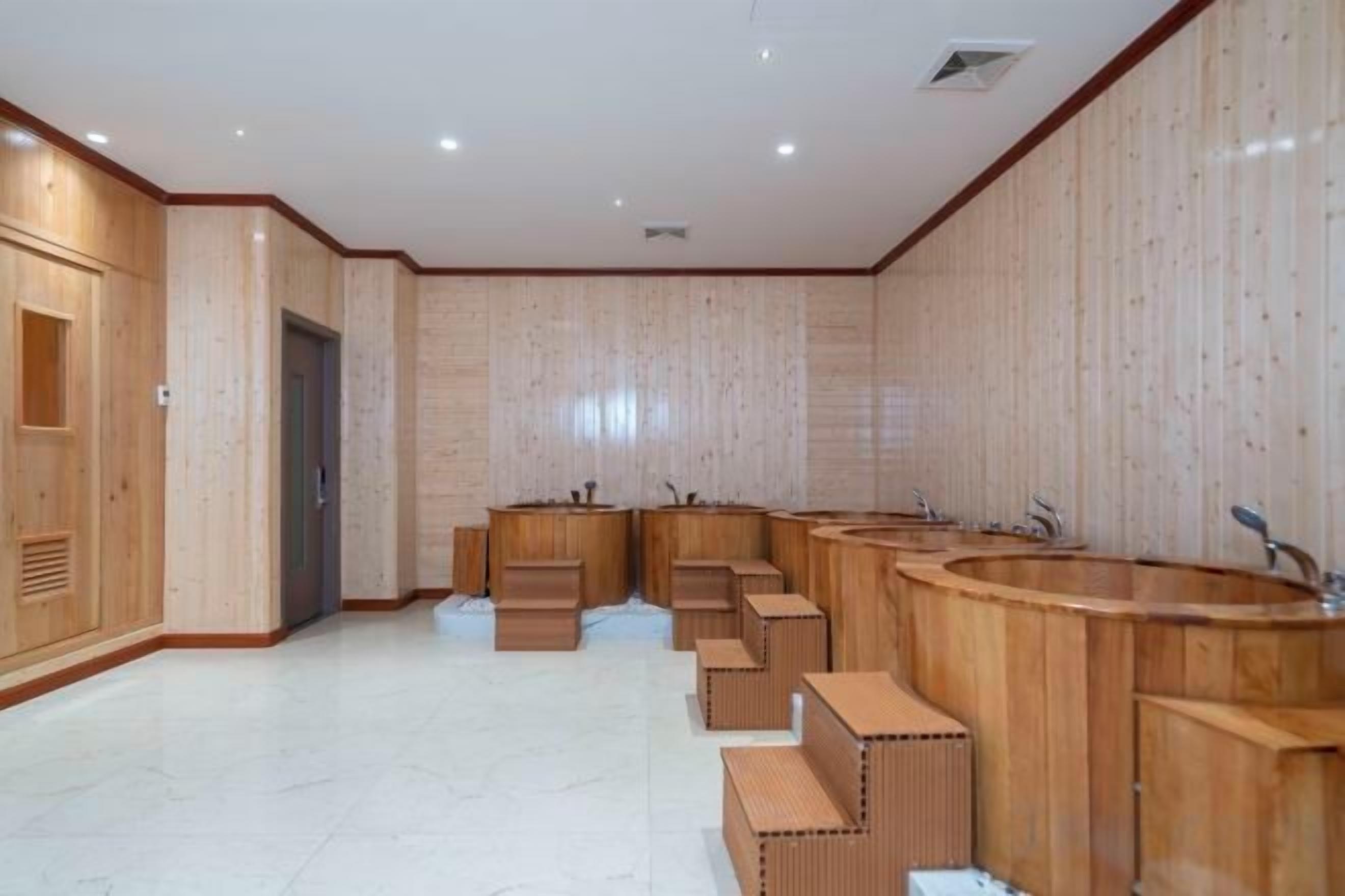 A sauna room with wooden benches and a large central bathtub.