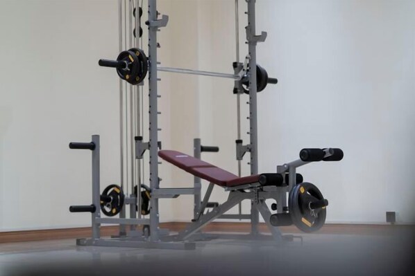 A gym with a bench press, squat rack, and weight plates. - Hung Vuong Hotel (Mong Cai)