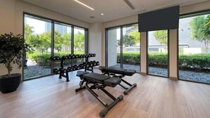A gym with exercise equipment, large windows, and a potted plant. - bnbme Chic Apt w/ Balcony, 5 min to Burj Khalifa (Dubai)