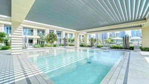 A modern indoor swimming pool with a tiled floor and a ceiling with horizontal slats. - bnbme Chic Apt w/ Balcony, 5 min to Burj Khalifa (Dubai)