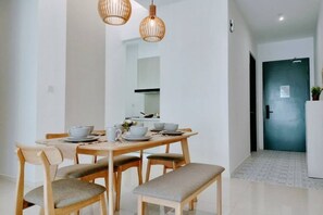 A dining area with a wooden table, four chairs, a bench, and two hanging pendant lights.