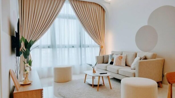Ein modernes Wohnzimmer mit Sofa, Hocker, Couchtisch und Vorhängen.