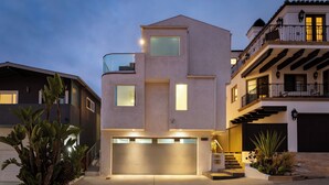 Una casa moderna de varios pisos con garaje, ventanas amplias y un balcón.
