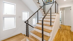 Una escalera de madera con barandales de metal que lleva a un rellano con un cuadro enmarcado.