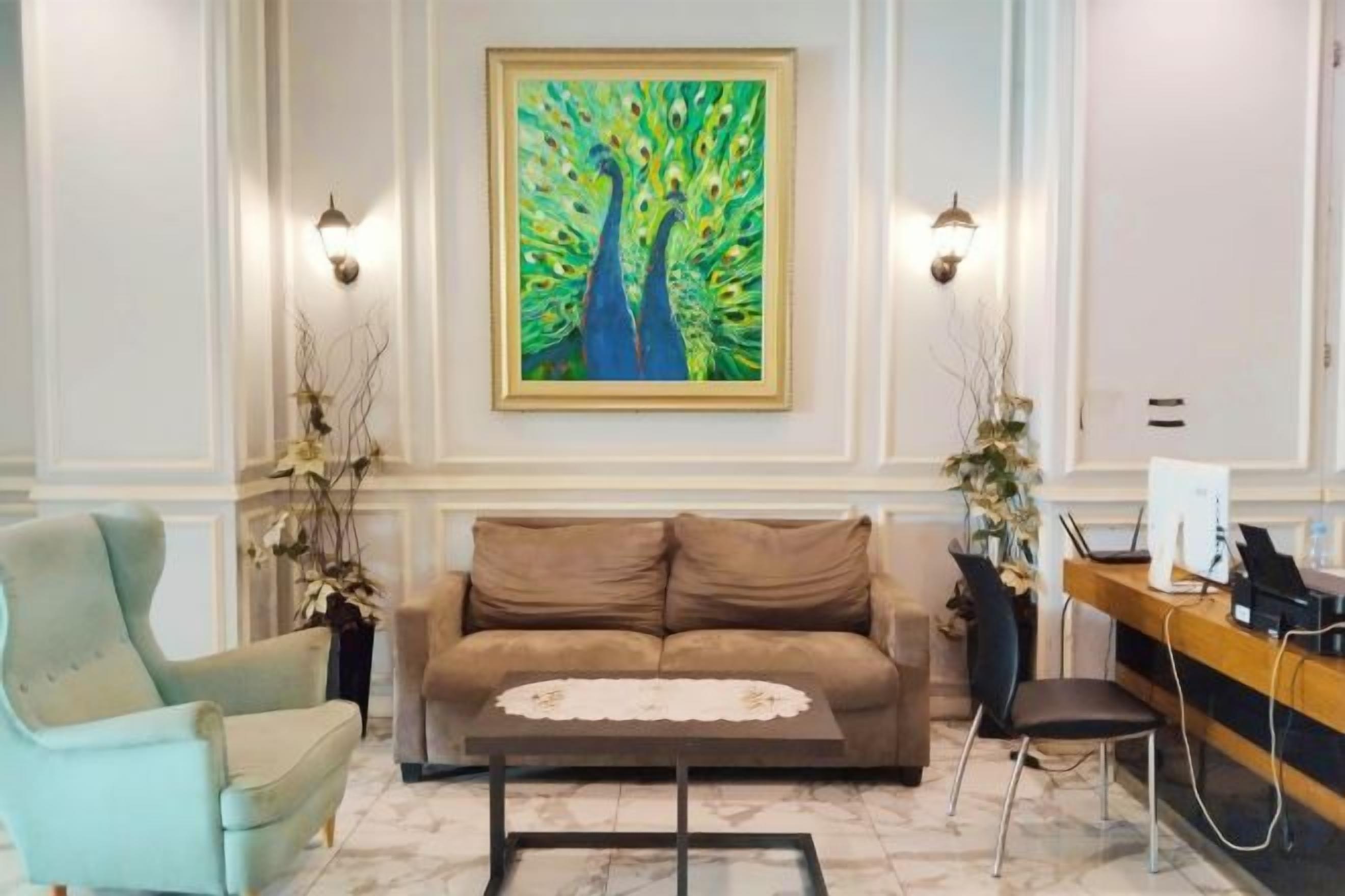 A room with a sofa, a chair, a desk, and a painting on the wall.