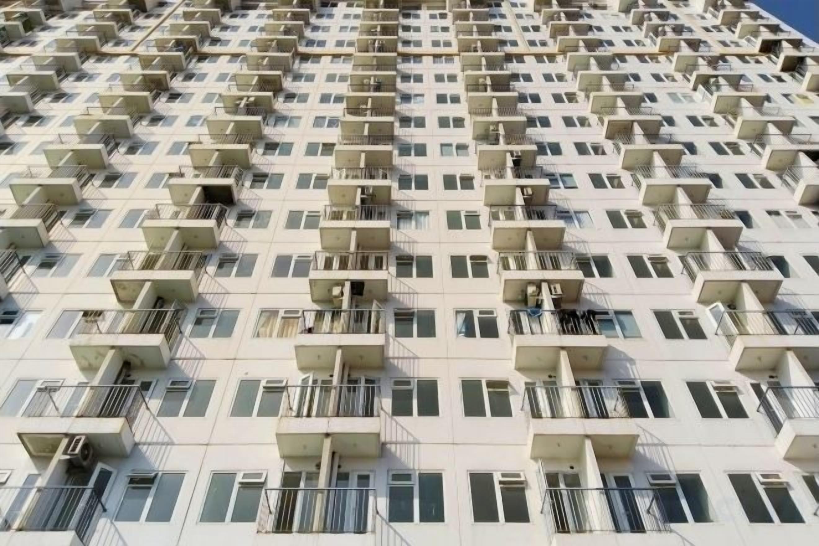 A high-rise building with multiple balconies and air conditioning units.
