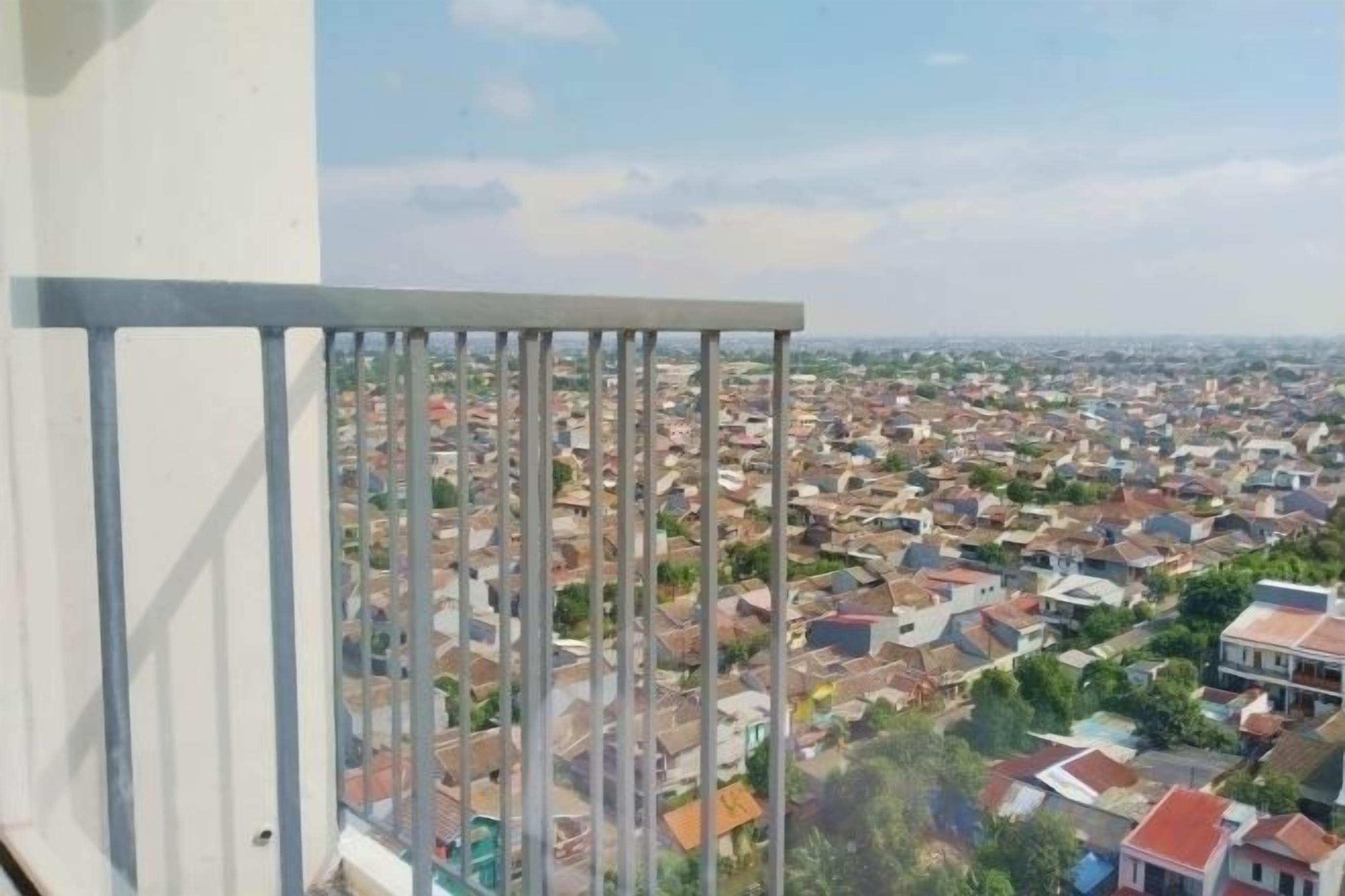 A balcony with a metal railing overlooking a densely packed residential area.