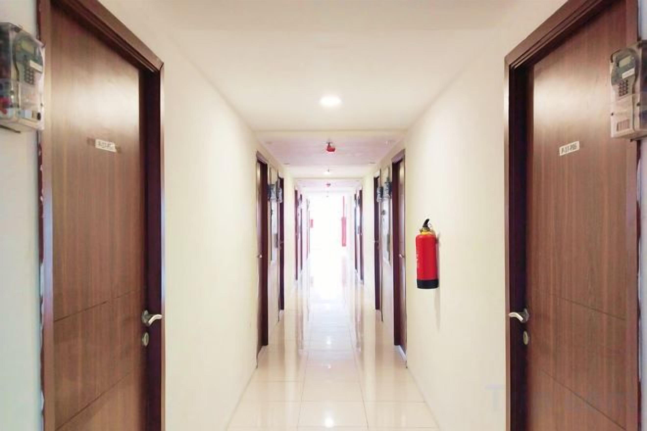 A hotel corridor with wooden doors, a fire extinguisher, and a ceiling light.