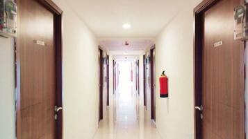A hotel corridor with wooden doors, a fire extinguisher, and a ceiling light.