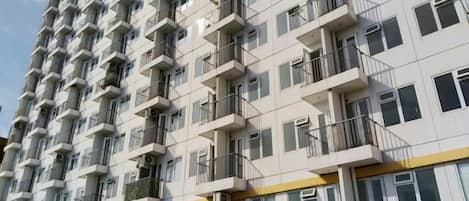 A multi-story residential building with balconies, windows, and a yellow stripe on the lower facade.