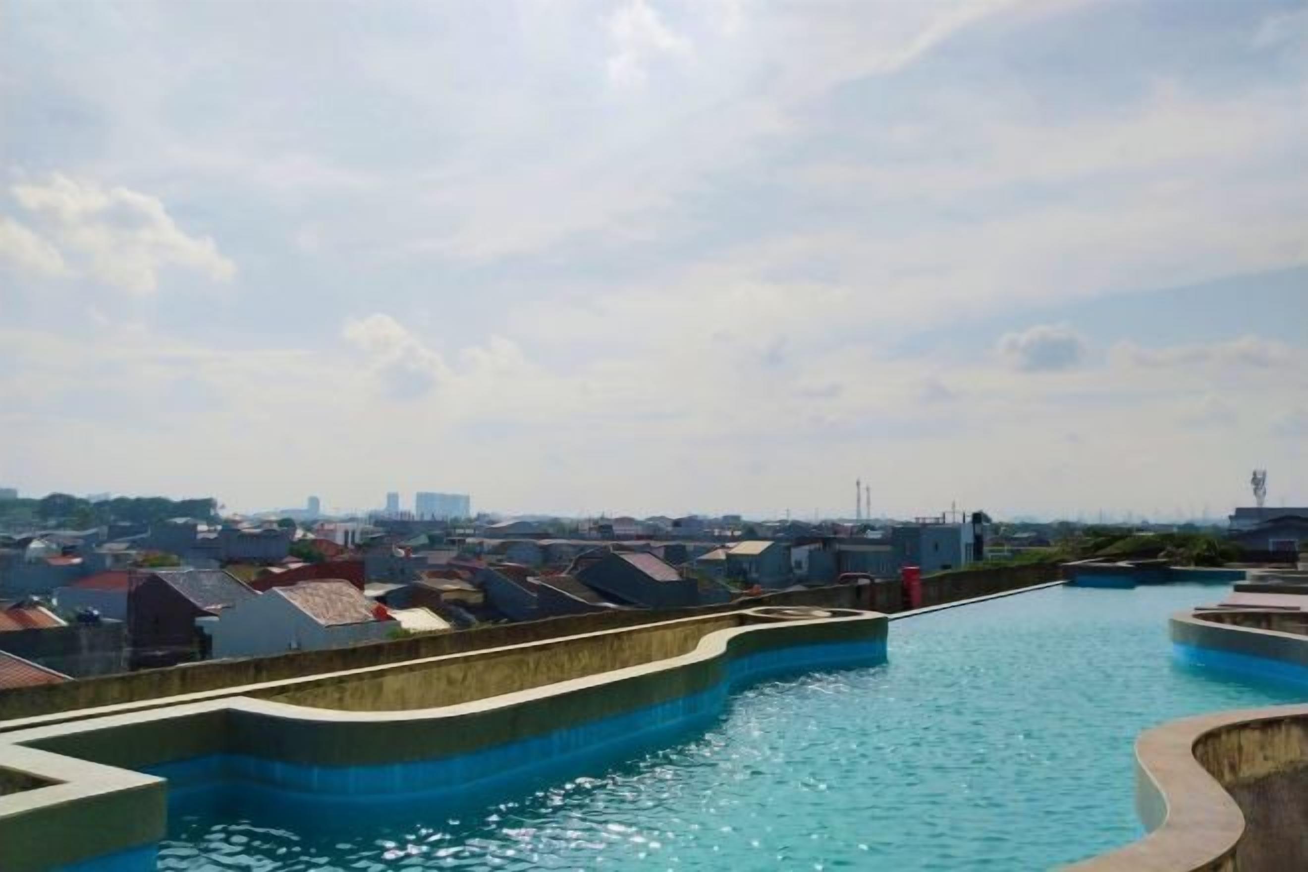 Une propriété située au bord de l’eau, dotée d’une piscine, d’une structure en béton aux lignes courbes et offrant une vue sur le paysage urbain en arrière-plan.