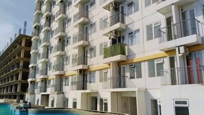 A multi-story hotel with balconies, a swimming pool, and a clear sky.