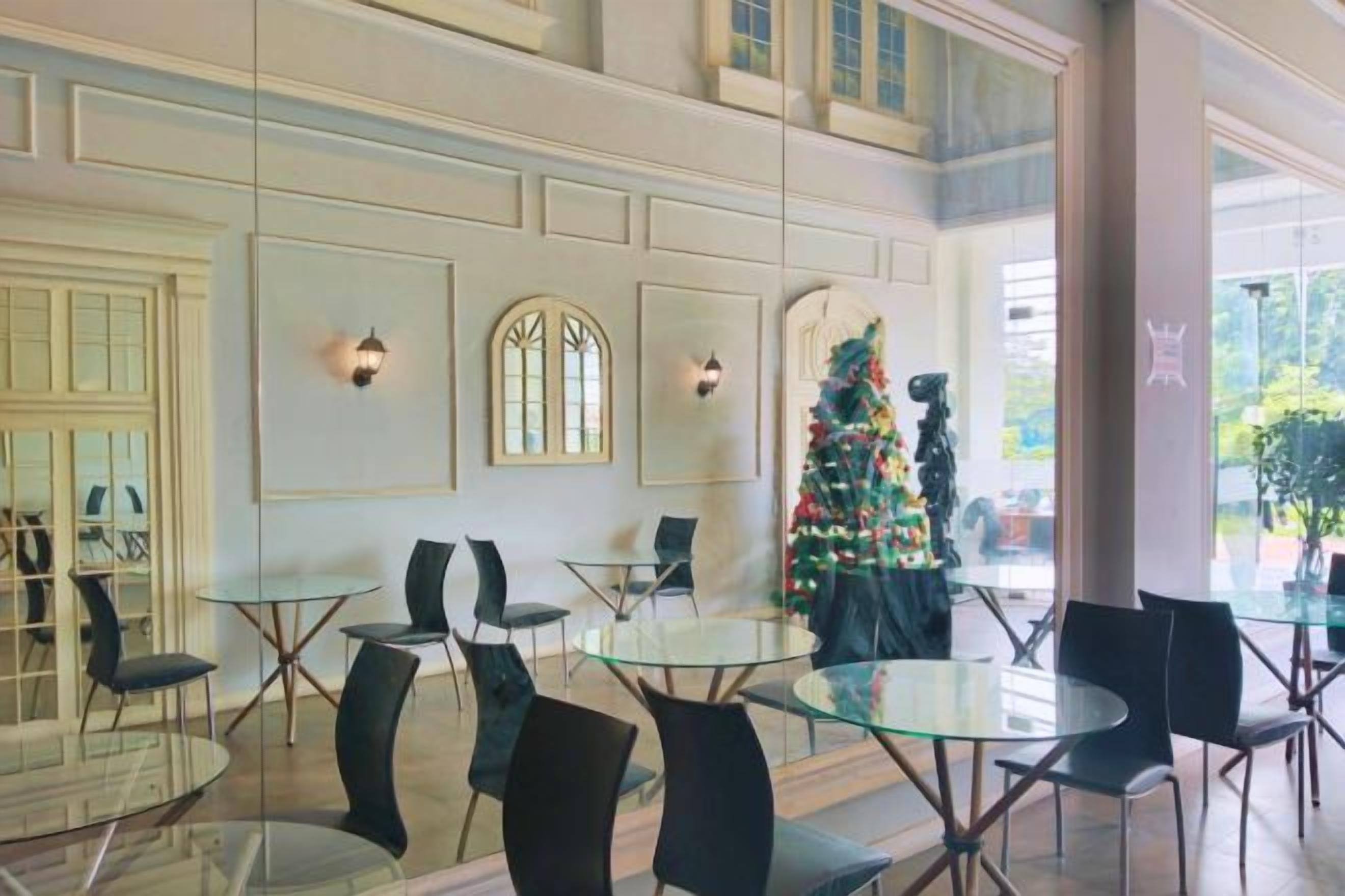 Eine Lobby mit runden Tischen und Stühlen, ein Weihnachtsbaum und ein großes Fenster.