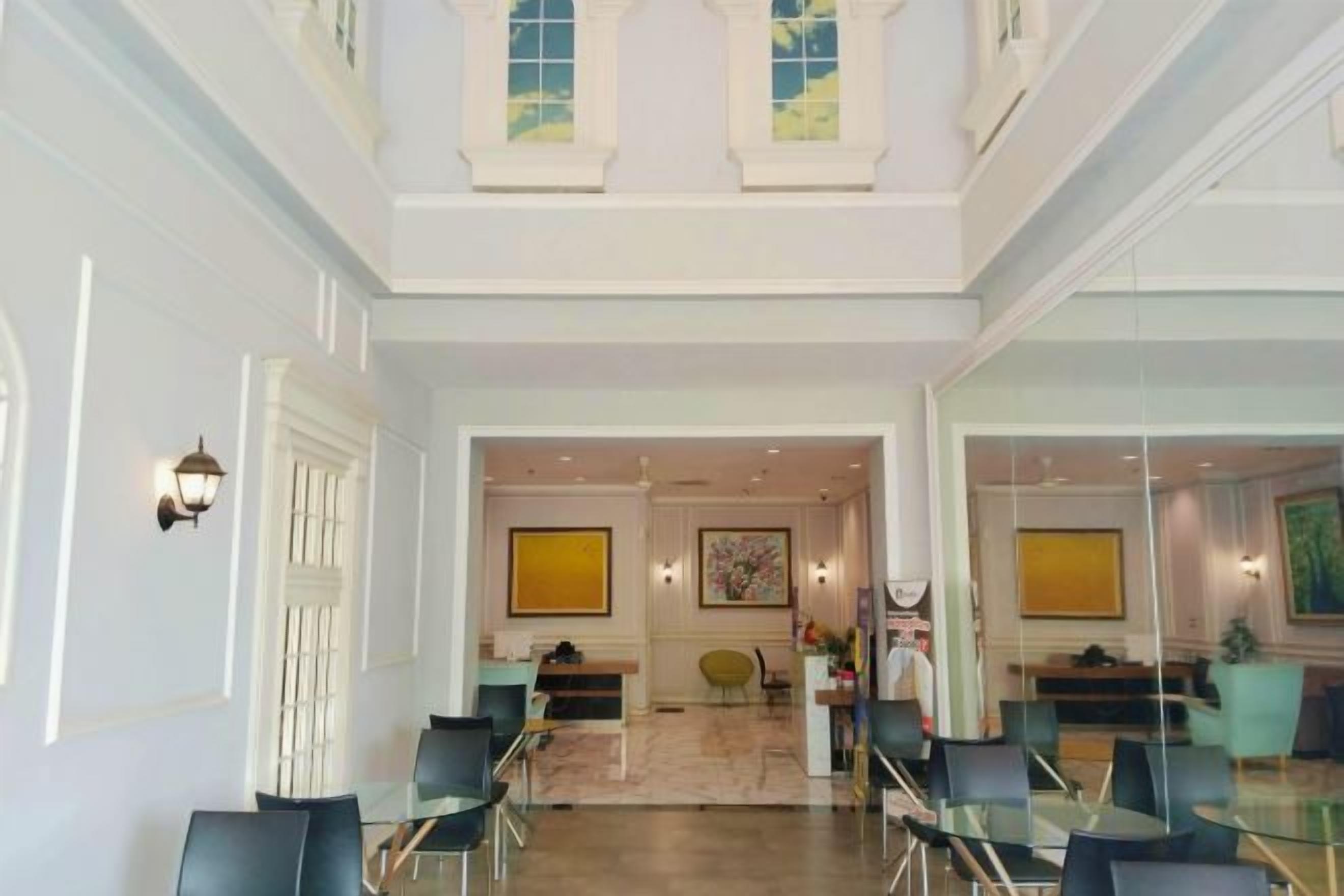 A spacious lobby with a high ceiling, a central seating area, and a view into another room.