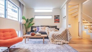 A modern living room with a sofa, a coffee table, and a bright window. - Ikebukuro Japandi Villa (Tokyo)