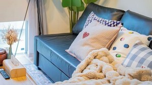 A modern living room with a blue sofa, a heart-shaped pillow, and a fluffy beige blanket. - Ikebukuro Japandi Villa (Tokyo)