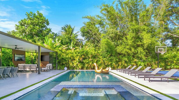A swimming pool with a floating duck decoration, surrounded by lounge chairs and a covered seating area with tables and chairs.
