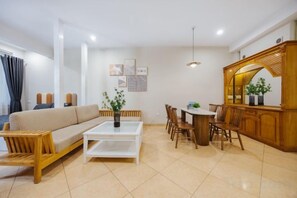 A living room with a sofa, coffee table, and dining area with chairs and a table. - VietHOME - 22 Pho Hue - Duplex 3 4 (Hanoi)