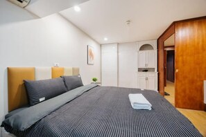 Una habitación de hotel con cama, mesita de noche, una pequeña mesa y un armario.