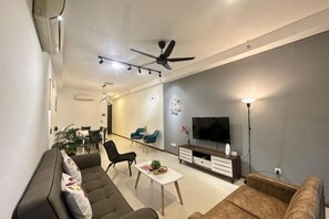 Una sala de estar moderna con sofá, sillas, televisor y ventilador de techo.
