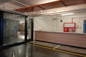 Eine helle, moderne Lobby mit einer Rezeption, einer Glastür und einem an der Wand befestigten Feuerlöscher.