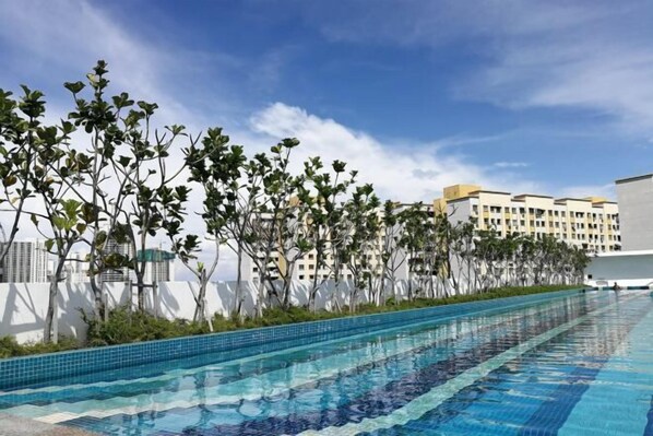 Ein Schwimmbad mit klarem, blauem Wasser, umgeben von Grünflächen und modernen Gebäuden im Hintergrund.