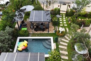 A rooftop pool with a slide, surrounded by a garden with a patio area. - Baanjeab in khaoyai (Pak Chong)