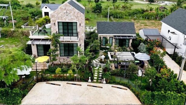 A modern house with a stone facade, large windows, and a well-maintained garden. - Baanjeab in khaoyai (Pak Chong)