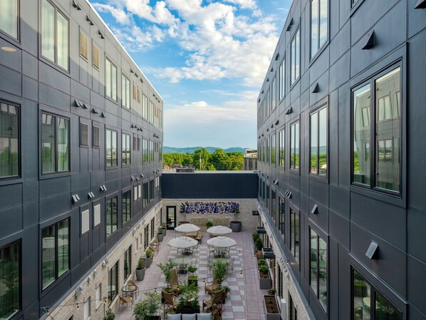 A modern building with a courtyard featuring outdoor seating and potted plants.