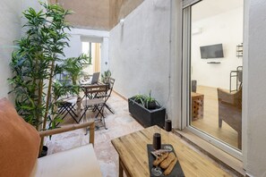 Ein gemütlicher Patio-Bereich mit Holztisch, Stühlen und Blumentöpfen.
