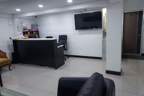 A reception area with a desk, a television mounted on the wall, and a door labeled 'Lobby'.