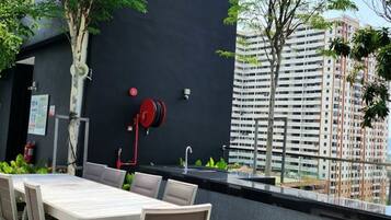 An outdoor dining area with a table and chairs, a fire extinguisher, and a view of a high-rise building.